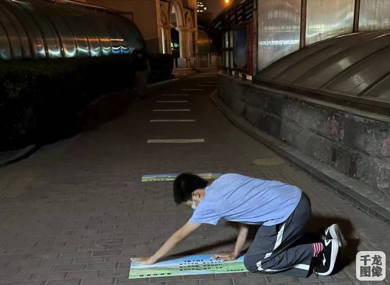 沈俊博和家人打印图片，并粘贴在地面上。千龙网发